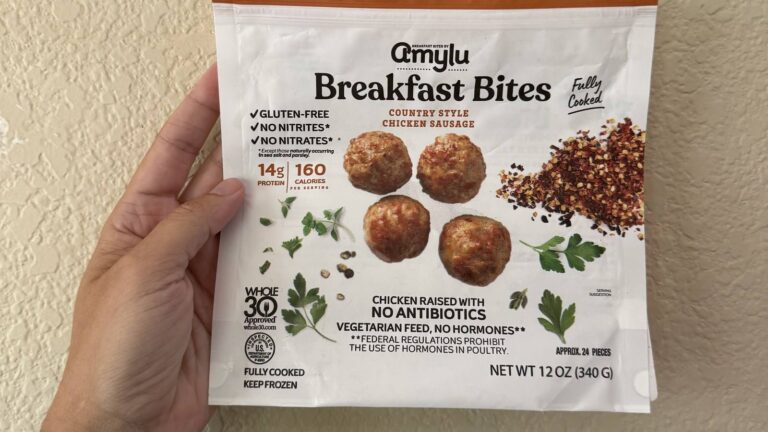 A hand holding a package of frozen chicken sausage bites covered in gluten-free and Whole30 label claims.