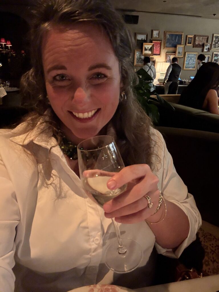 Nichole of Alpha Celiac Gal with a glass of wine in the dining room at Le Ame, the Parisian steakhouse at The Global Ambassador in Phoenix